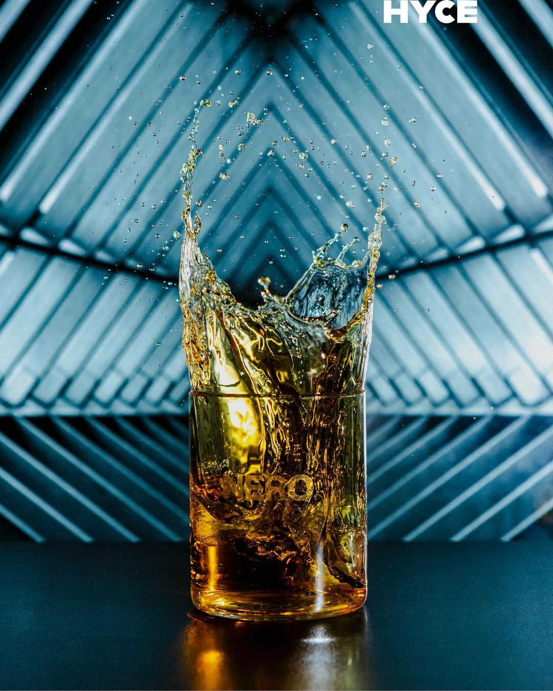 Un drink ambrato che schizza fuori dal bicchiere sotto luci blu